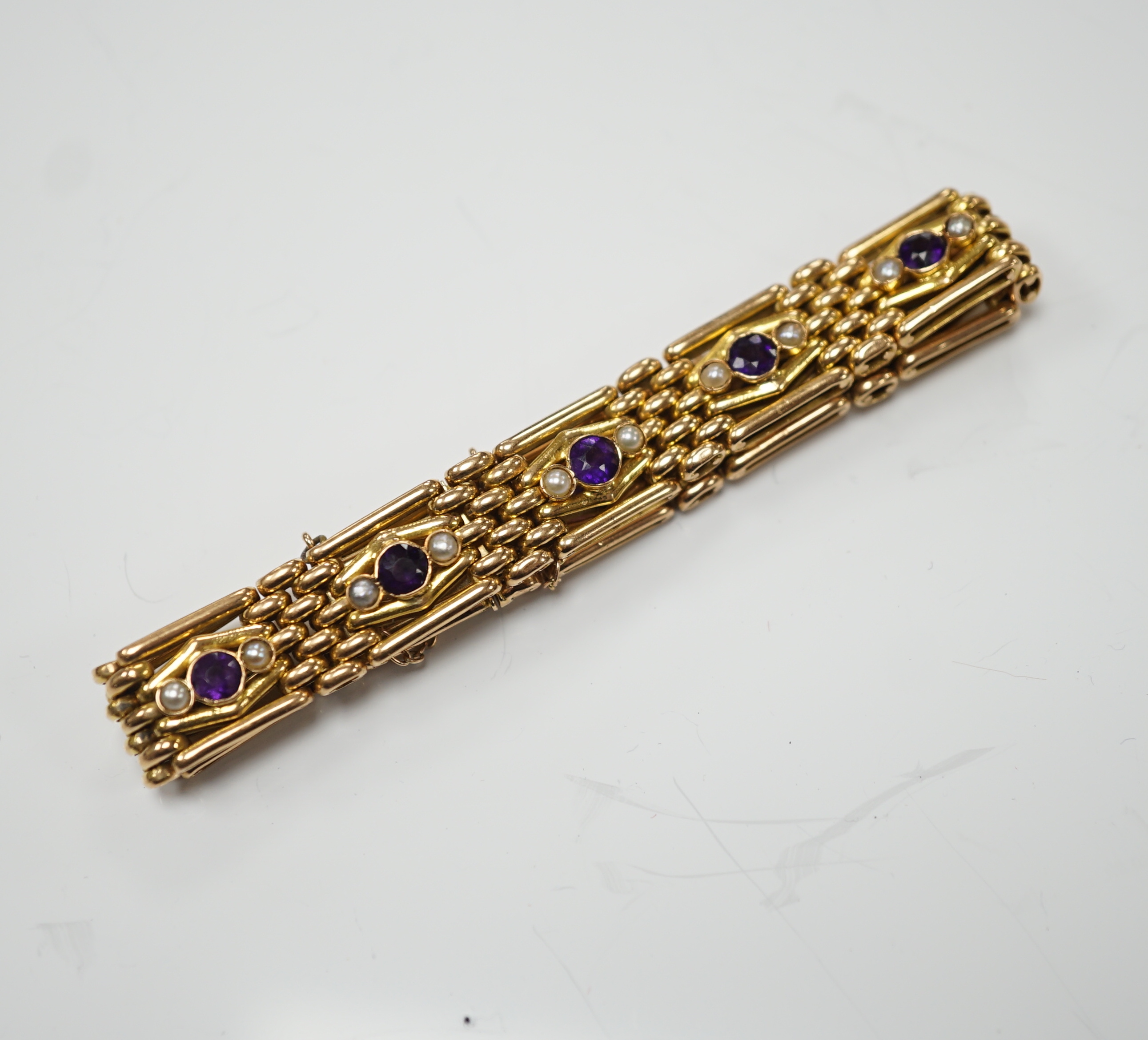 An Edwardian 15ct, amethyst and seed pearl set gate link bracelet, 18cm